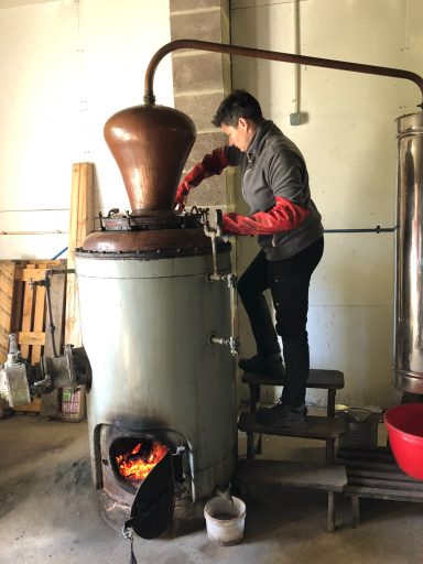 Aurélie, distillatrice en train d'ouvrir son alambic encore brulant du feu de bois