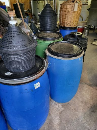 Tonneaux de fruits accompagnés de leurs bonbonnes en attente de la distillation